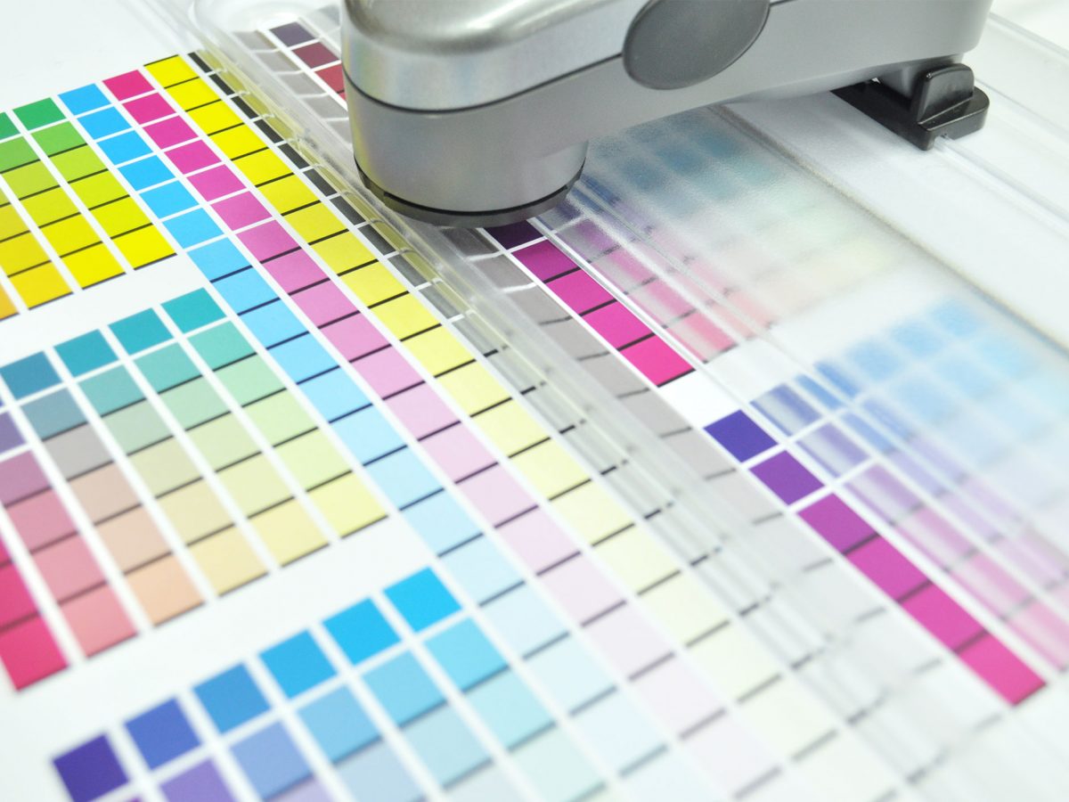 Spectrophotometer scanning printed colour swatches for colour accuracy in print quality control.